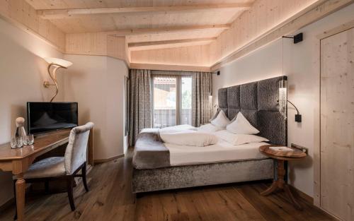 アルペ・ディ・シウージにあるHotel Rosa Eco Alpine Spaのベッドと机とテレビのある寝室