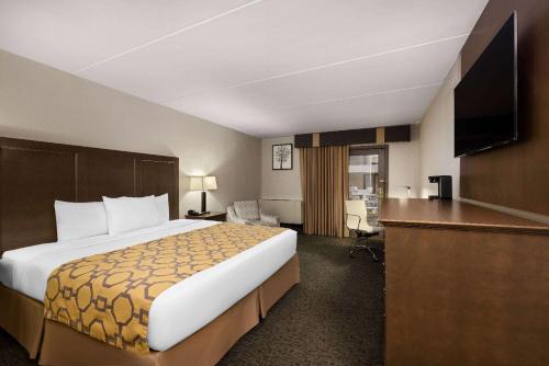 a hotel room with a large bed and a desk at Baymont by Wyndham Shakopee in Shakopee