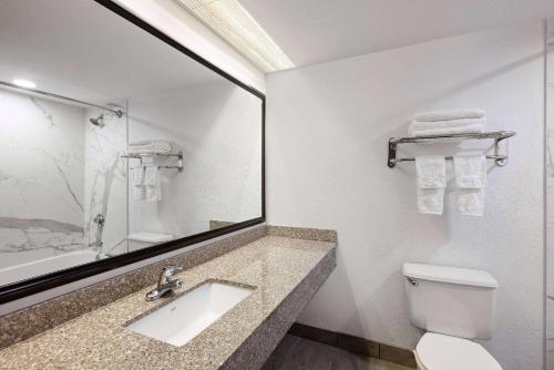 a bathroom with a sink and a toilet and a mirror at Baymont by Wyndham Shakopee in Shakopee
