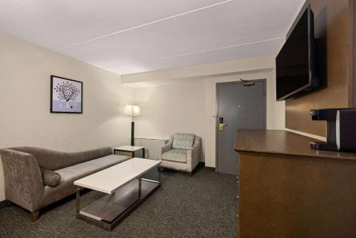 a living room with a couch and a tv in a hotel room at Baymont by Wyndham Shakopee in Shakopee