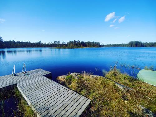 un muelle en un lago con dos sillas. en Kalliorinteen Mökit Ruskapirtti en Töysä