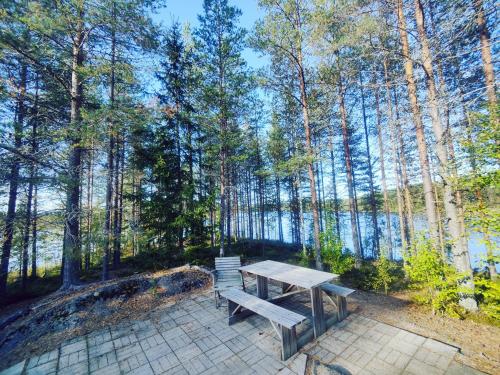 a picnic table in the woods next to a lake at Kalliorinteen Mökit Ruskapirtti in Töysä