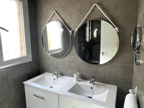 a bathroom with two sinks and two mirrors at Málaga casa grande familiar in Málaga