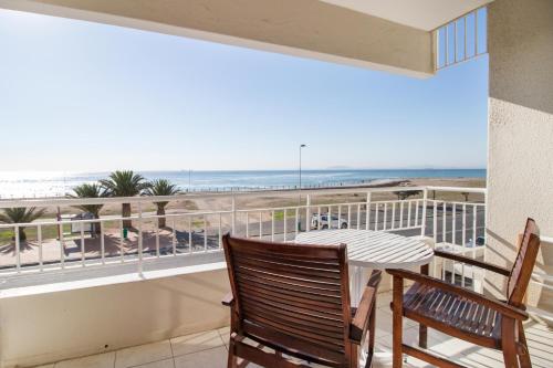 a balcony with a table and chairs and a view of the beach at Mouille Point Places - Studios & Apartments in Cape Town