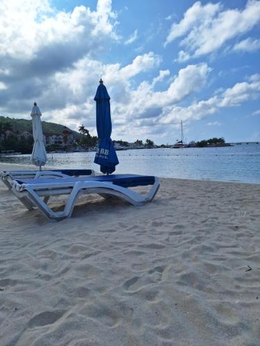 two lounge chairs with umbrellas on a beach at Beach One Bedroom 2 in Ocho Rios