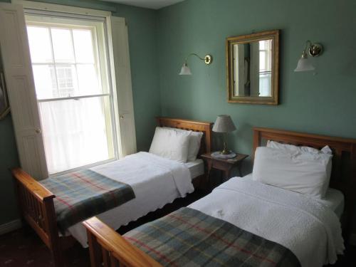 a bedroom with two beds and a mirror and a window at Darcus Cottage in Derry Londonderry