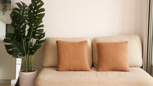 a couch with two pillows and a plant at R Home Staycation - Niagara Tower in Manila