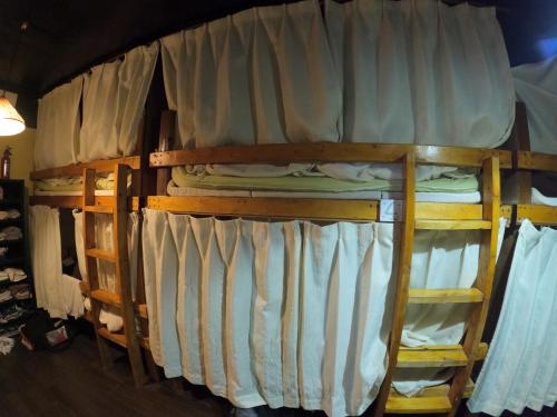 a bunk bed with white curtains on it at Zamamia International Guesthouse in Shimajiri