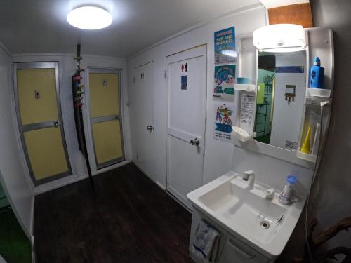 La salle de bains est pourvue d'un lavabo et d'un miroir. dans l'établissement Zamamia International Guesthouse, à Shimajiri