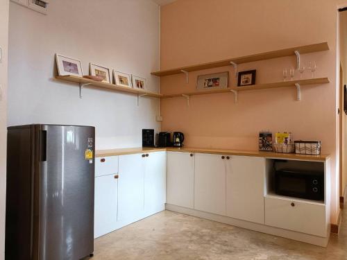 een keuken met witte kasten en een roestvrijstalen koelkast bij Family Room by 233Poshtel in Lampang