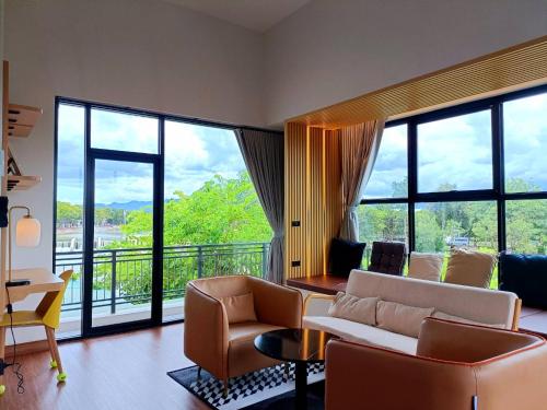 a living room with a couch and chairs and windows at Family Room by 233Poshtel in Lampang