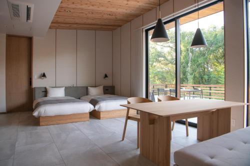 1 dormitorio con 2 camas y mesa con sillas en SOOTHE FOREST en Shio