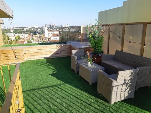 a rooftop patio with chairs and grass on a building at La Terrasse - big apartment & terrace 80m2 - metro 17 min from Paris in Bagneux