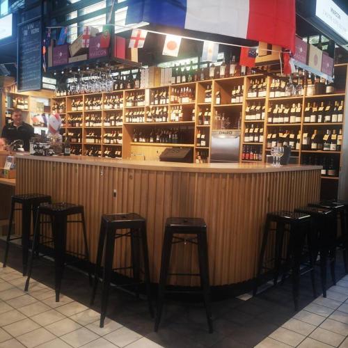 - un bar avec tabourets dans une pièce avec bouteilles de vin dans l'établissement Appartement Cosy, à Saint-Étienne