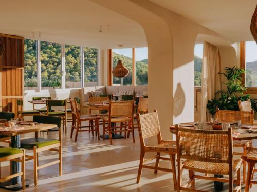 a restaurant with tables and chairs and windows at Hyde Ibiza in Cala Llonga