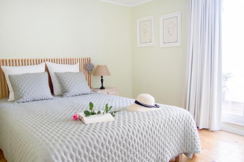 Una cama blanca con sombrero y flores. en Casa da Avó Guilhermina en Leiria