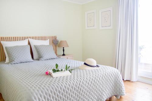 un letto bianco con un cappello e fiori sopra di Casa da Avó Guilhermina a Leiria