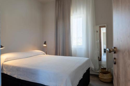 a white bed in a room with a window at Palia Kleopatra in Kalymnos