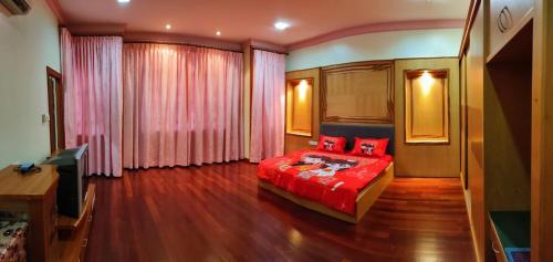 a bedroom with a red bed and a television at R&S Homestay Sibu - Wedding House with Large Parking Area and High Speed Unifi in Sibu