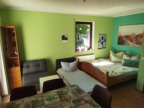 uma sala de estar com paredes verdes, um sofá e uma mesa em Ferienwohnung Nordlicht em Großdubrau