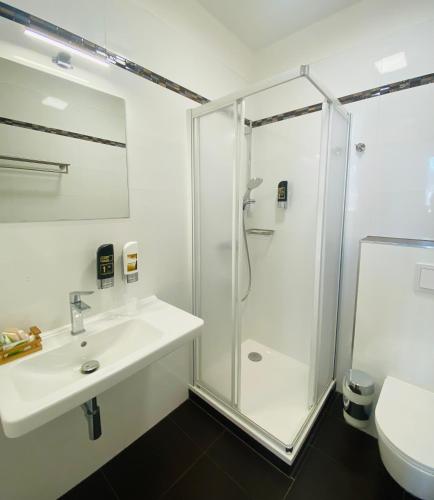 a white bathroom with a shower and a sink at Riverside Hotel Plzeň in Plzeň