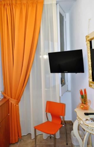 a room with an orange chair and a television at Hotel des Artistes in Naples