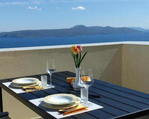 a table with plates and a vase with a flower on it at Holiday house Mavi -Obrs Moscenicka Draga,Riviera Opatija in Mošćenička Draga