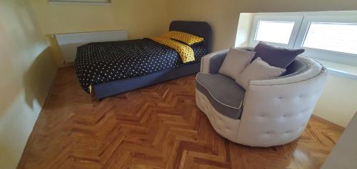 een slaapkamer met een bank, een bed en een stoel bij Apartman Queen in Pasuljište