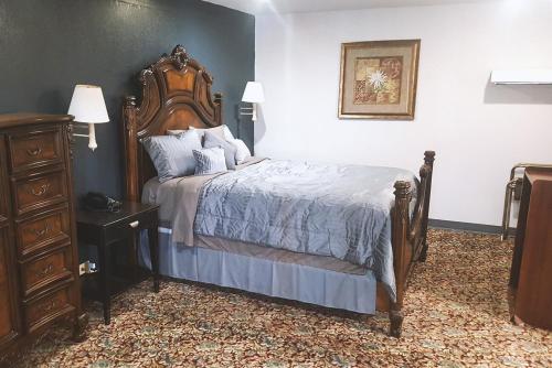a bedroom with a bed with a wooden headboard and a dresser at Sky-Palace Inn & Suites Hutchinson in Hutchinson