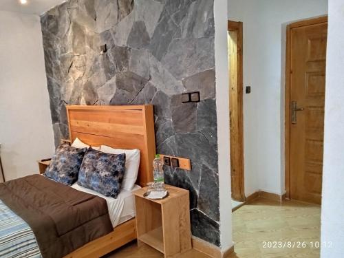 a bedroom with a rock wall next to a bed at Le Gite du Barrage in Zaouia Ben Smine
