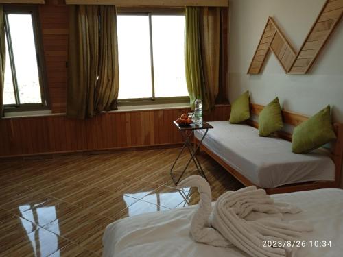 a hotel room with two beds and two windows at Le Gite du Barrage in Zaouia Ben Smine