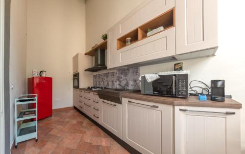 uma cozinha com armários brancos e um frigorífico vermelho em Fabroniana apartment Elegant em Pistoia