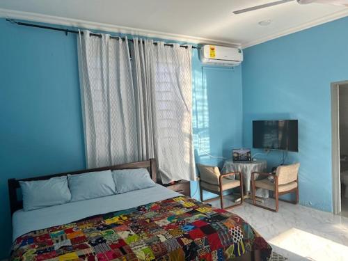 Schlafzimmer mit blauen Wänden, einem Bett und einem Tisch in der Unterkunft Oneworld Guesthouse & and Events Centre in Accra