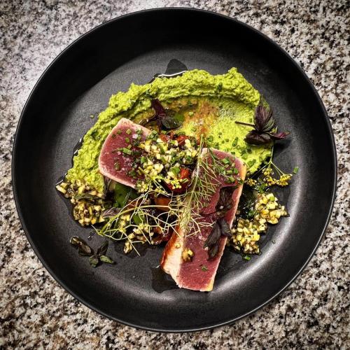 a black plate with food on a table at Logis Hôtel Restaurant La Bergerie in Aragon
