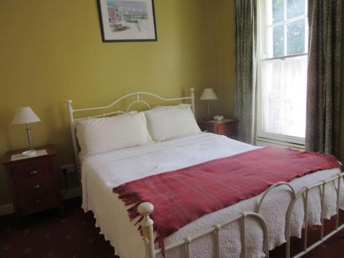 a bedroom with a white bed with a red blanket at Cathedral Cottage in Derry Londonderry