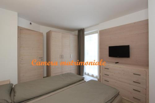 - une chambre avec un lit et une télévision à écran plat dans l'établissement Residence Alpen Park, à Molveno