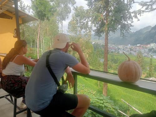 a man and a woman sitting at a window looking at a pumpkin at Đồng Văn Panorama Homestay in Dồng Văn