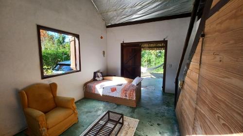a bedroom with a bed and a chair and a window at Canto do Riacho Chales in Trindade