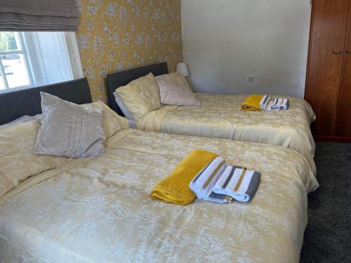 two beds with towels on them in a room at Holland Arms Hotel in Llangristiolus