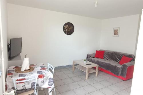 a living room with a couch and a table at studio sympa au rez de chaussée in Denain