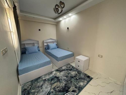 two beds in a small room with blue sheets at Apartment Hossam 1 in Hurghada