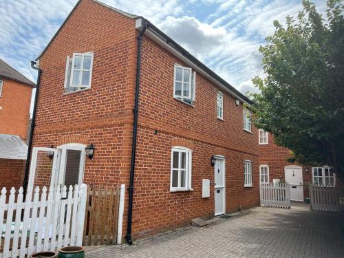 a red brick building with a white fence at Mews house in the centre of Henley-on-Thames in Henley on Thames