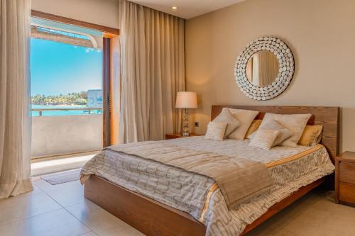 sypialnia z dużym łóżkiem i dużym oknem w obiekcie Beachfront Luxurious Stunning Sunset Boulevard Apartment, Grand Baie w mieście Grand Baie