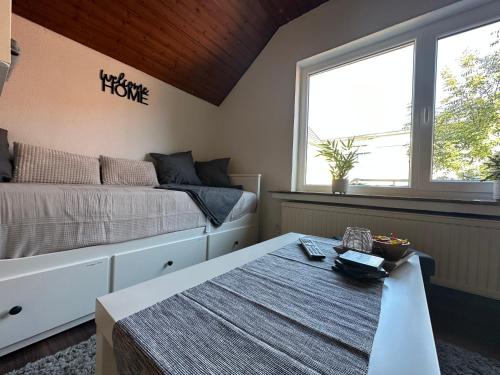 a bedroom with a bed and a table and a window at Sauerlandapartment Vivien in Plettenberg