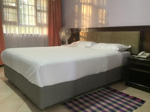 a large bed in a hotel room with a phone at HOTEL HIPPO BUCK in Homa Bay