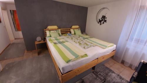 uma cama com lençóis e almofadas verdes e brancos em Ferienwohnung Heimsheim em Heimsheim