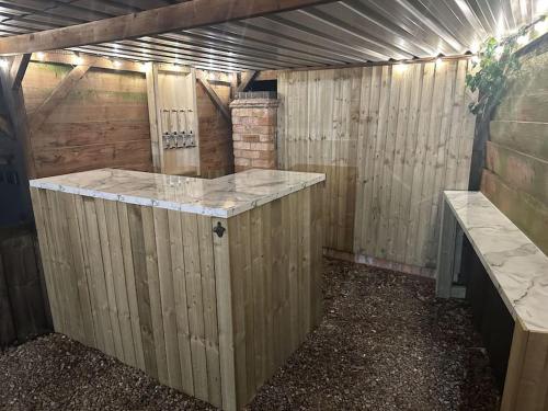 an outdoor shower in a wooden shed with a counter at The Coach House by Phoenix Premises - Hot Tub Fire Pit BBQ Log Burner Bar Games Room in Birmingham