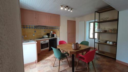 une cuisine avec une table en bois et des chaises colorées dans l'établissement Gîte La Source de Label, à Saint-Paul-des-Fonts