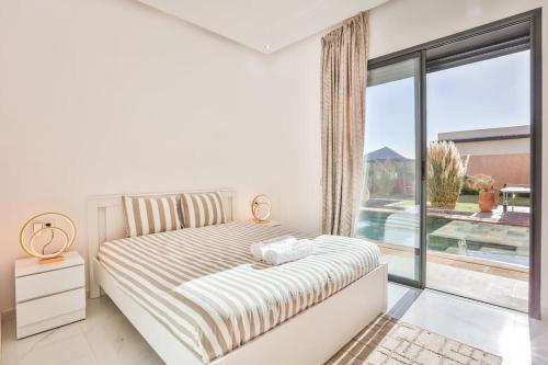 une chambre blanche avec un lit et une grande fenêtre dans l'établissement Villa Sakina, piscine Chauffée, ping-pong, cuisinière, à Marrakech