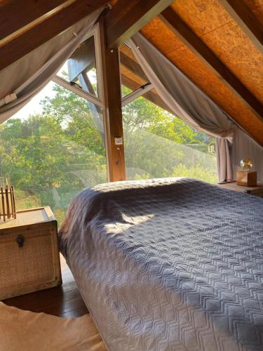 a bed in a room with a large window at Descanso do Rosa - cabanas charmosas in Imbituba